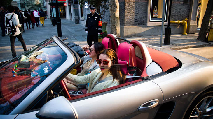 Dua gadis lokal mengendarai Porsche di dekat West Nanjing Road.